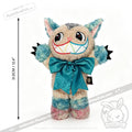 Victorian McGee's Autism Acceptance Cheshire Cat - Plush Stuffed Animal features multicolor fur, a large rainbow grin, a big blue bow, pointy ears, and claws. Shown against a white background with a vertical measurement indicating its height of 31.5 cm (12.4 inches), this whimsical plush toy is inspired by Alice in Wonderland and designed to celebrate autism acceptance.