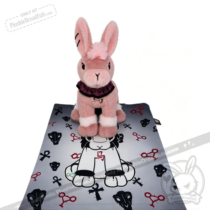 A pink Year of the Horse plush rabbit sits on a gray mat with black and red animal and key designs.